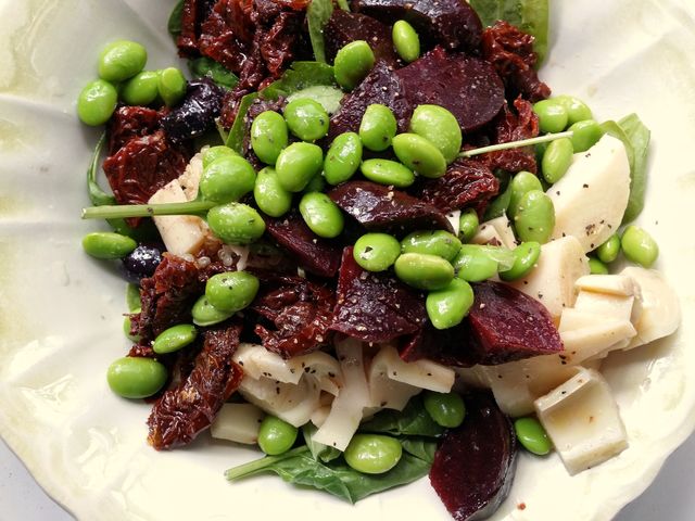 A colorful edamame beet sun dried tomato hearts of Palm and spinach salad