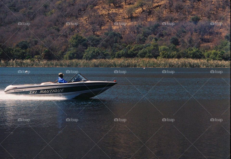 Guy in a boat on a lake.captured in motion with a 35mm Canon film camera.