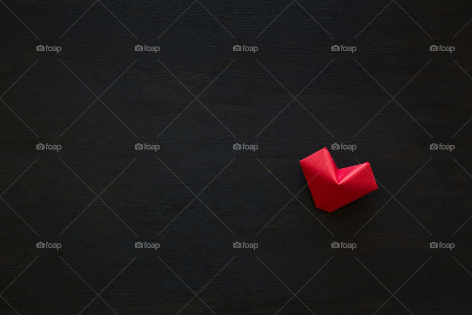 Origami red heart on black wood