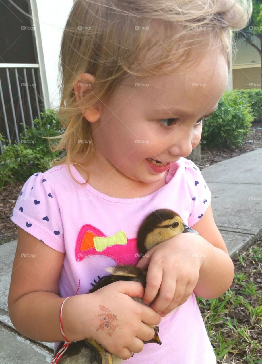 Cute girl holding duckling in hand