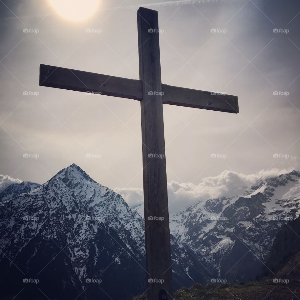 Cross on snow covered mountains against sky