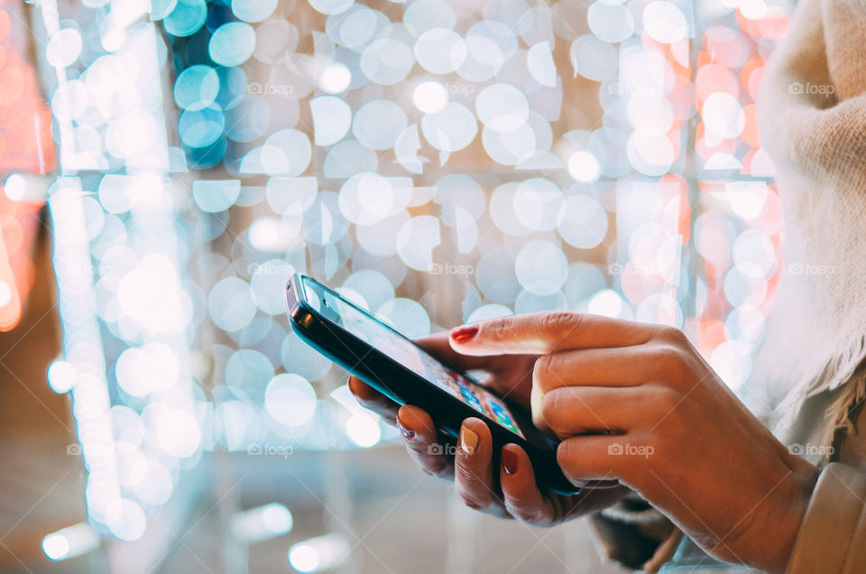 Woman using mobile at Christmas lights