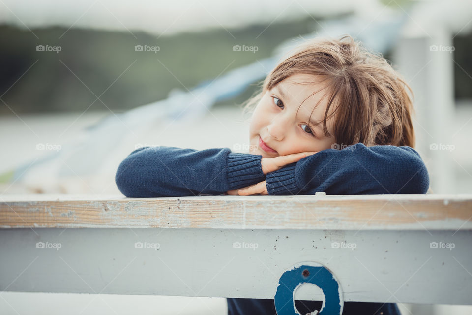 Little girl on lake coast at sunny evening. 