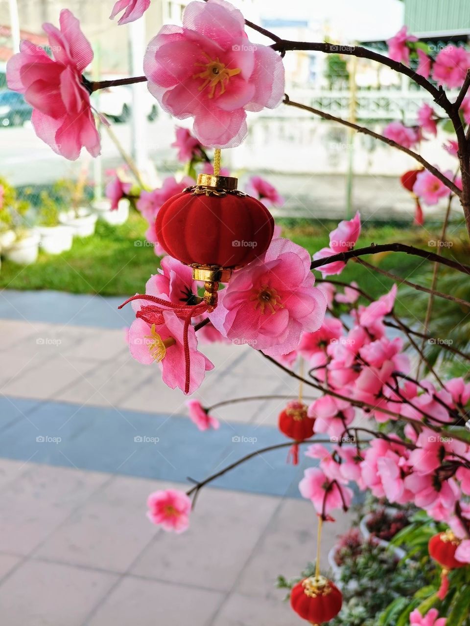The red lantern decoration hanging on the artificial plum blossom tree.