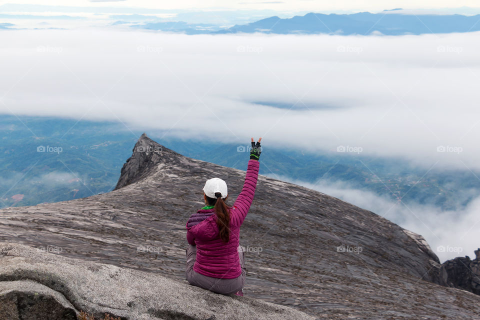 Young woman on top of Mt Kinabalu in Sabah Borneo, Malaysia enjoying the scenic view after the hardest climb