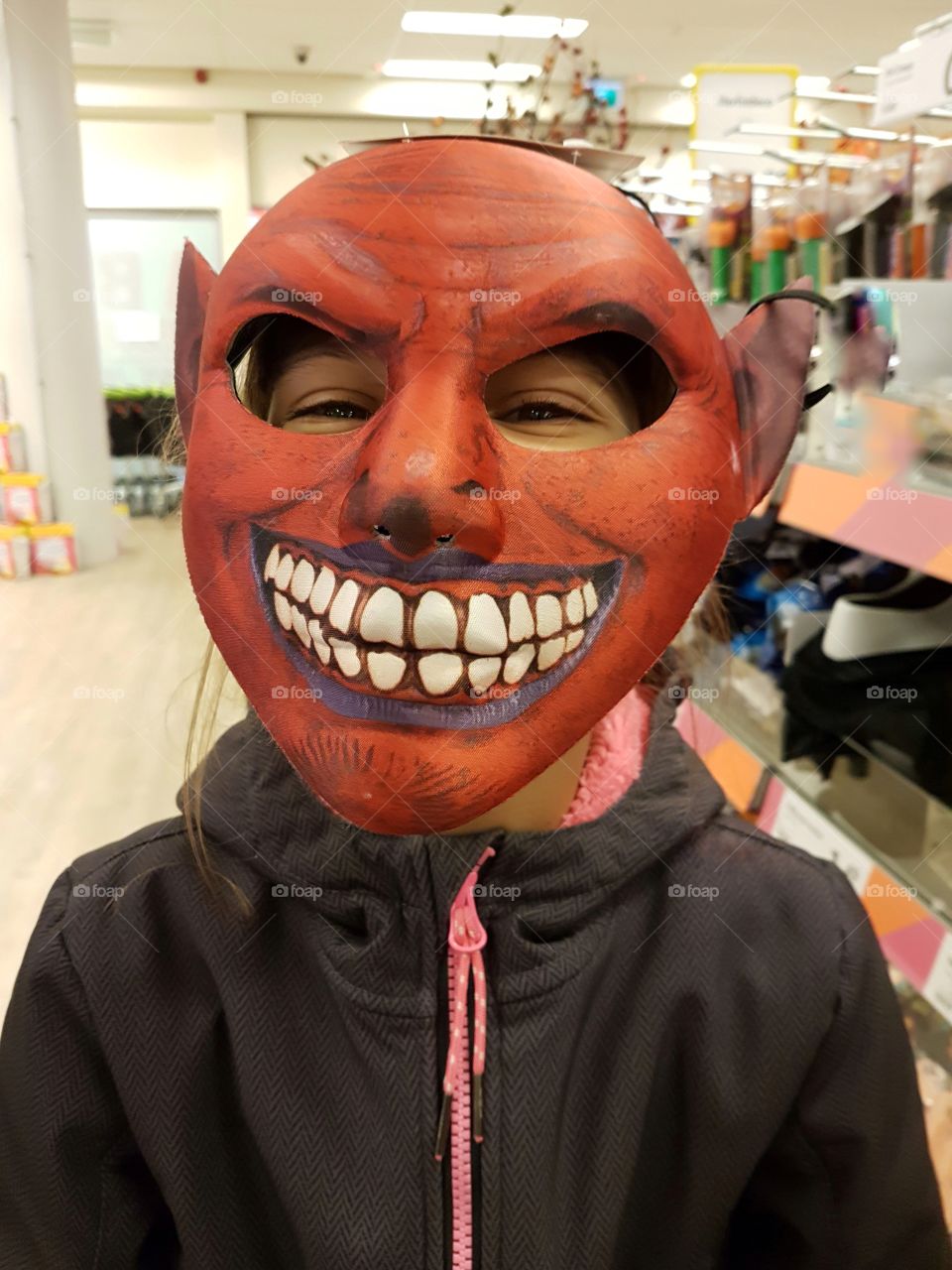 A girl in the red mask for Halloween in shop