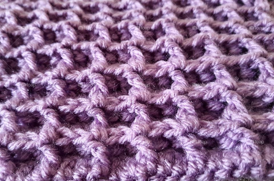 a close up view of a waffle stitch crocheted in purple yarn