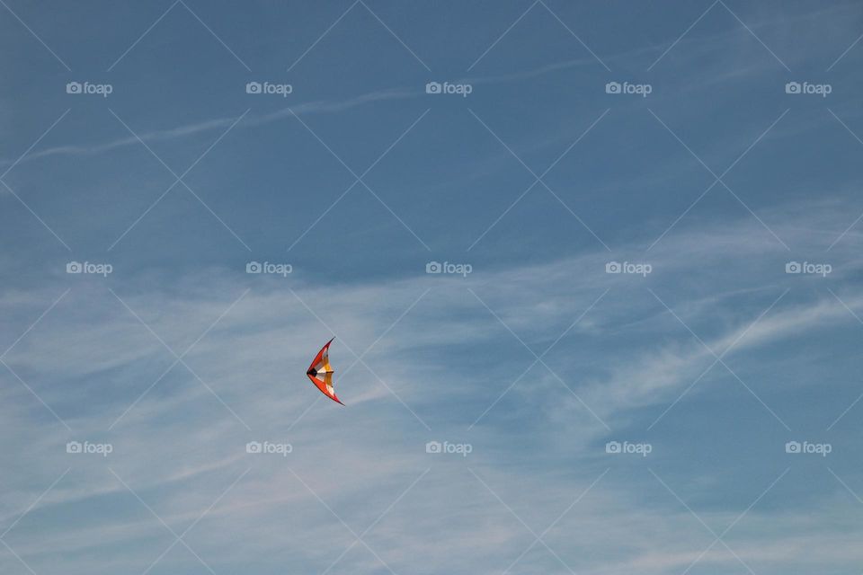 Close-up of an orange stunt kite in the blue sky
