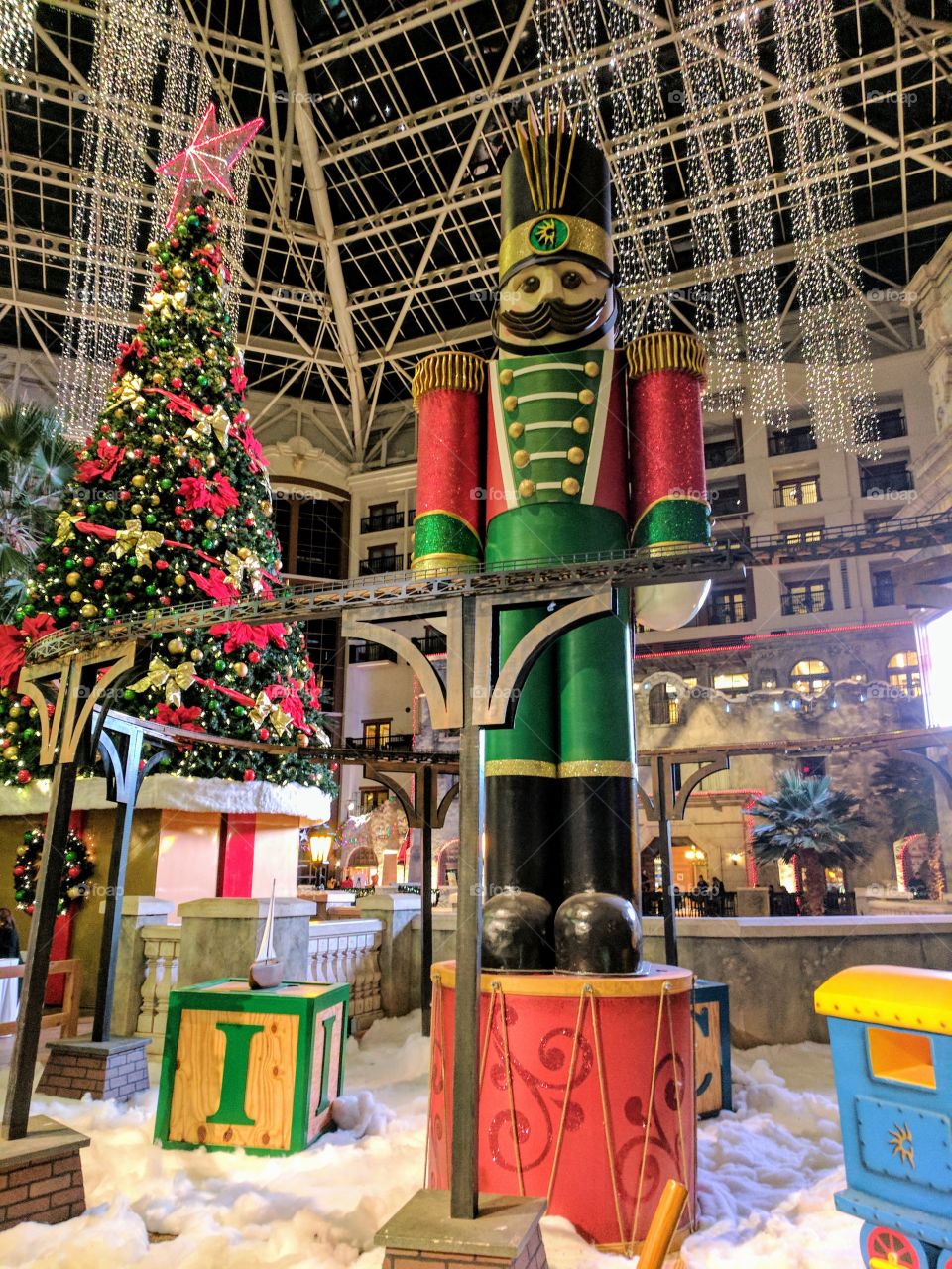 A larger than life nutcracker stands near a decorated Christmas tree