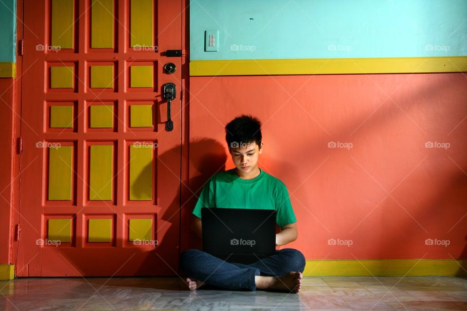 young asian teen with a laptop computer in a living room