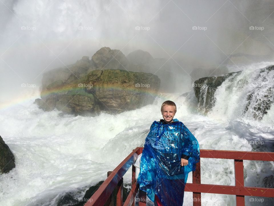 Boy standing in front of waterfall