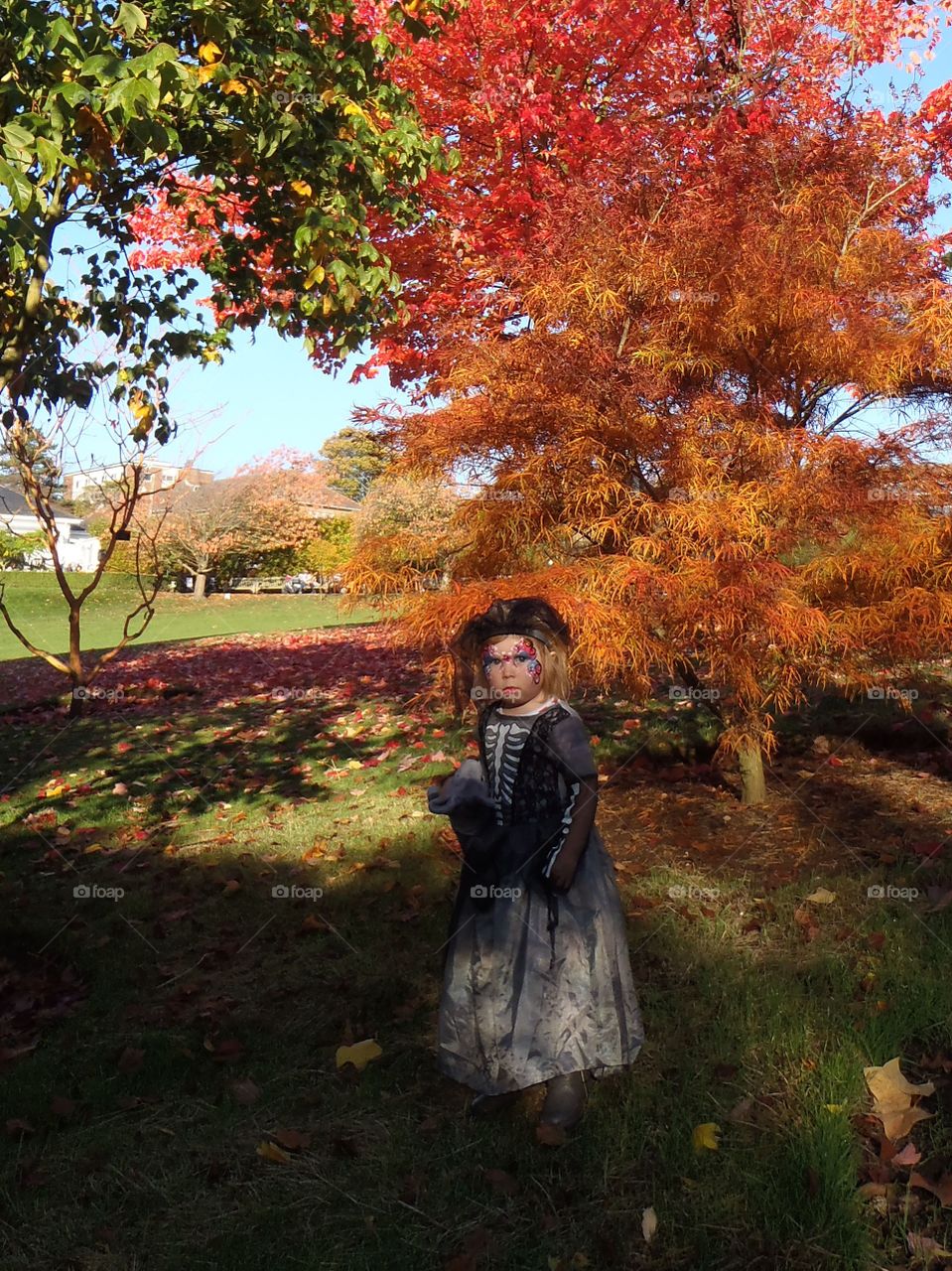 Girl dress up for halloween standing near autumn trees
