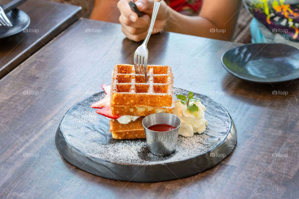 Waffle Strawerry fresh cream in the black plate on wooden table.