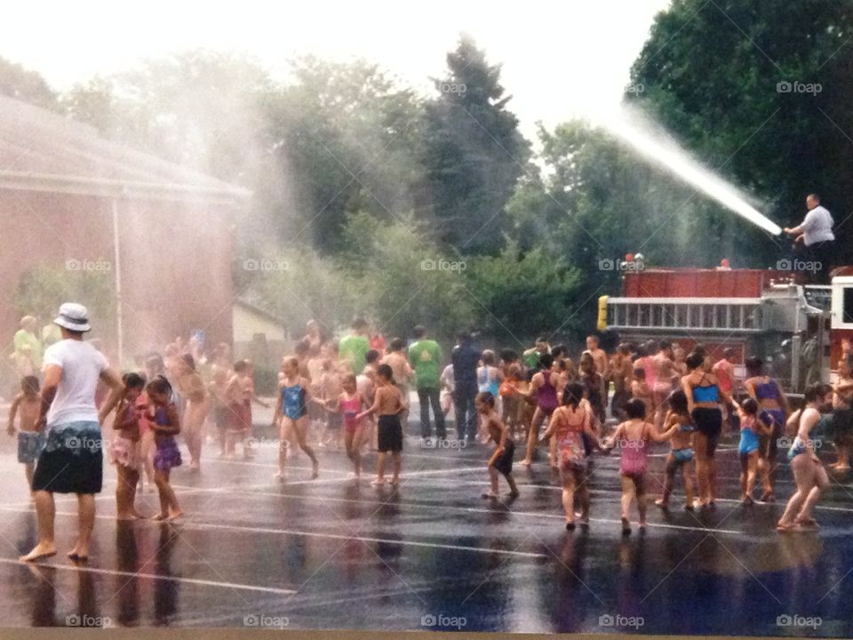 Fire truck spraying water on crowd of children