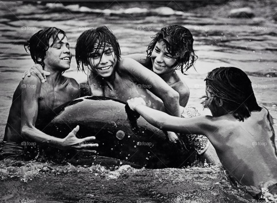 young boys play in an irrigation canal in mexico. central mexico inner tube. by arizphotog