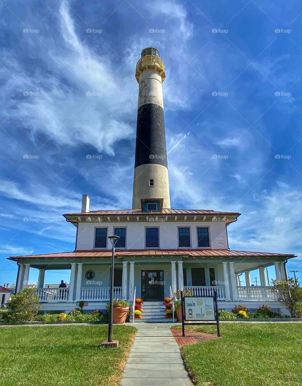 Abescon Lighthouse in Atlantic City, New Jersey, where it was relocated.  Lighthouse, tall, front porch, blue sky, wispy white clouds, beautiful 