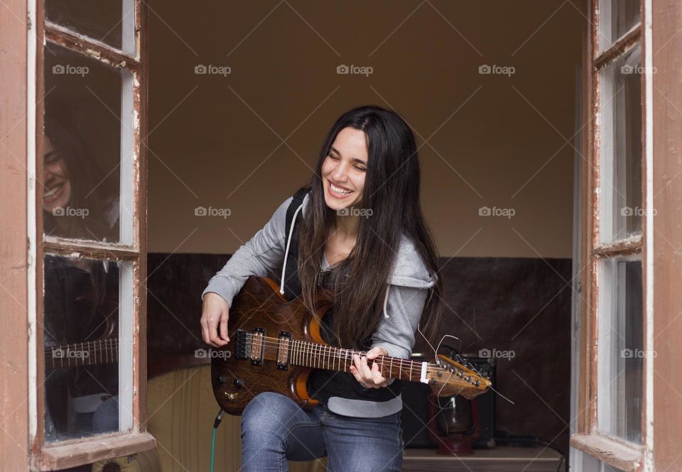 Guitar player woman on the window