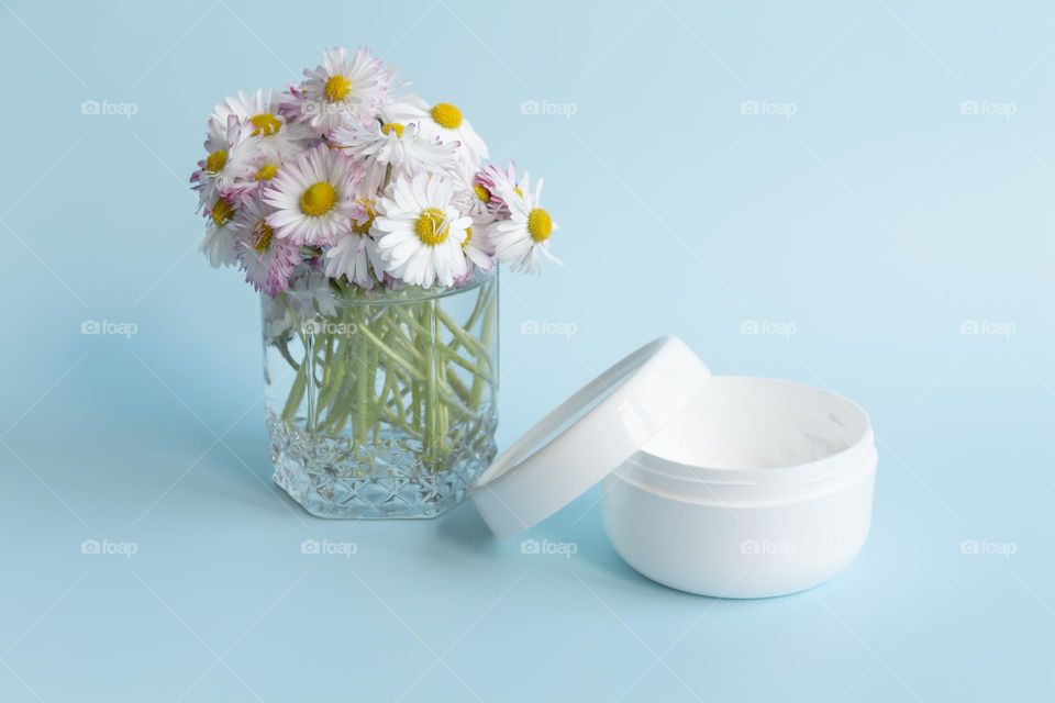 Jars with cosmetic products, beauty cosmetics in a white jar with cream and water with fragrant flowers.