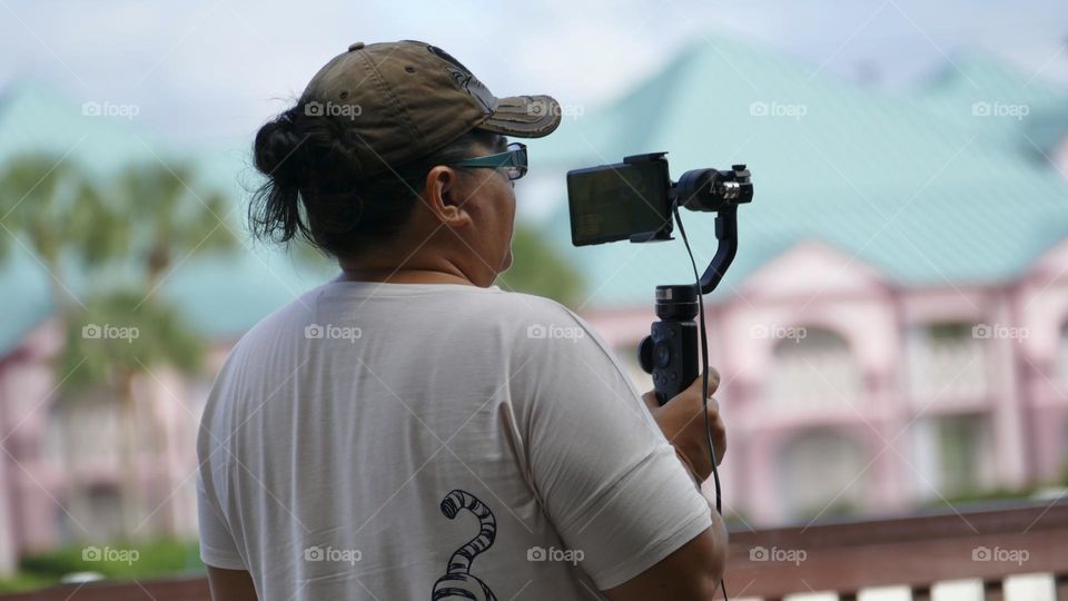 Video creator holding a camera on gimbal while recording outdoors 