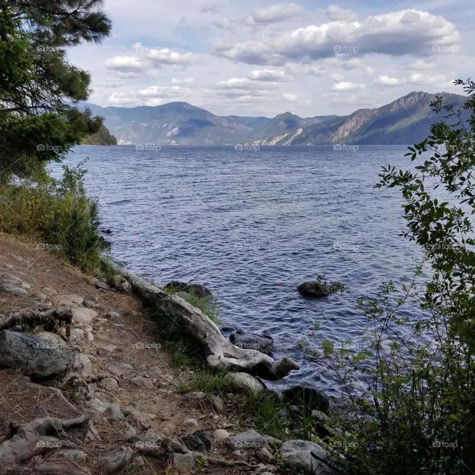 rocky shoreline view of lake and mountain ridge on a sunny day