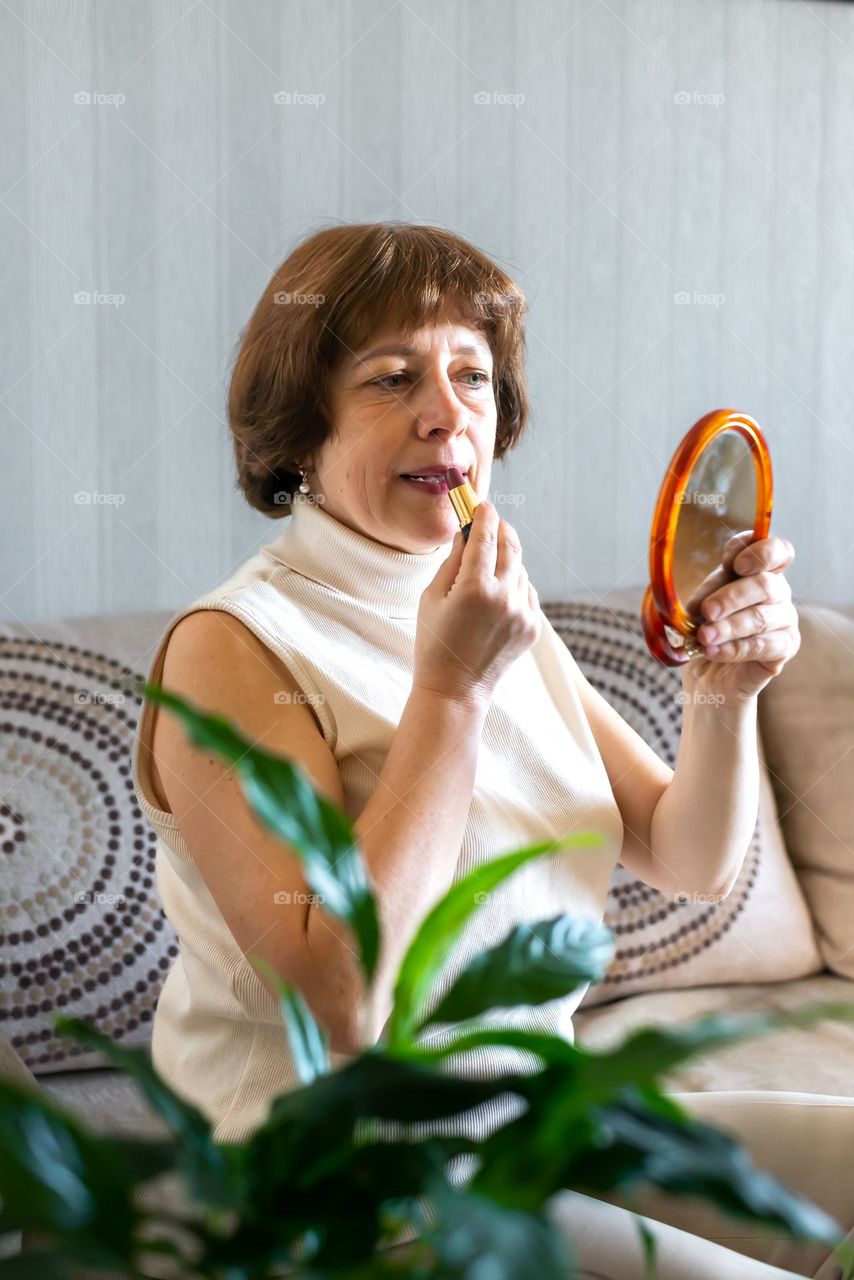 Home beauty salon woman paints her lips looking in the mirror