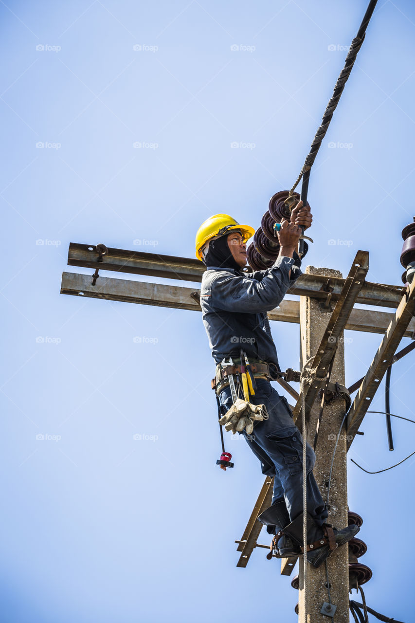 Electrician working on the electricity pole to replace the electrical insulator