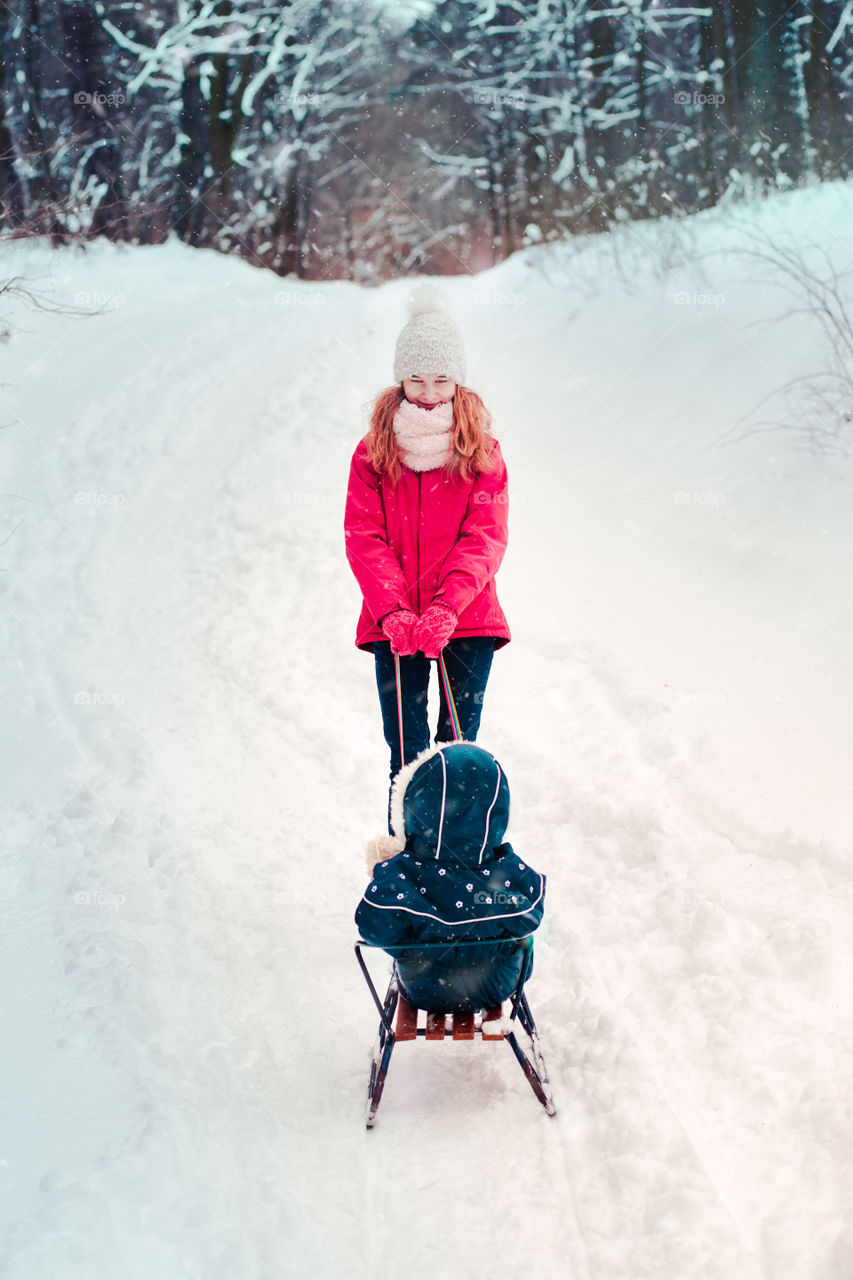 Teenage girl enjoying snow with her little sister enjoying wintertime