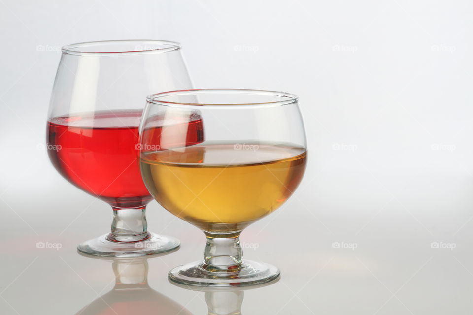 Red and white wine glass on white reflective background