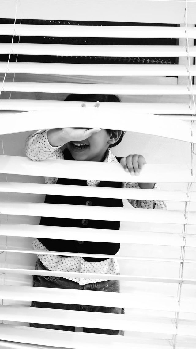 Little Boy Hiding Behind The Blinds