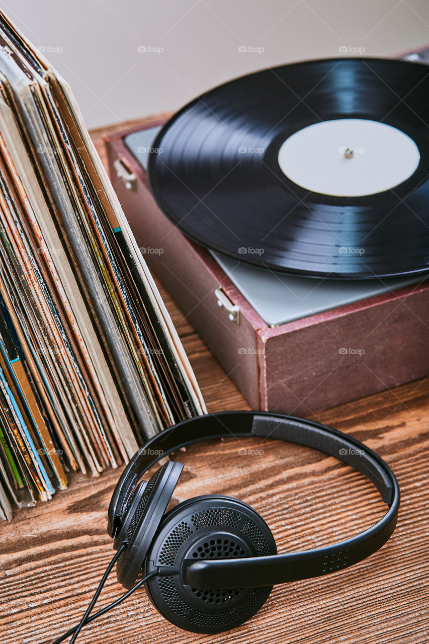 Stack of many black vinyl records, turntable vinyl player and headphones put on the stack. Classic stereo set. Candid people, real moments, authentic situations