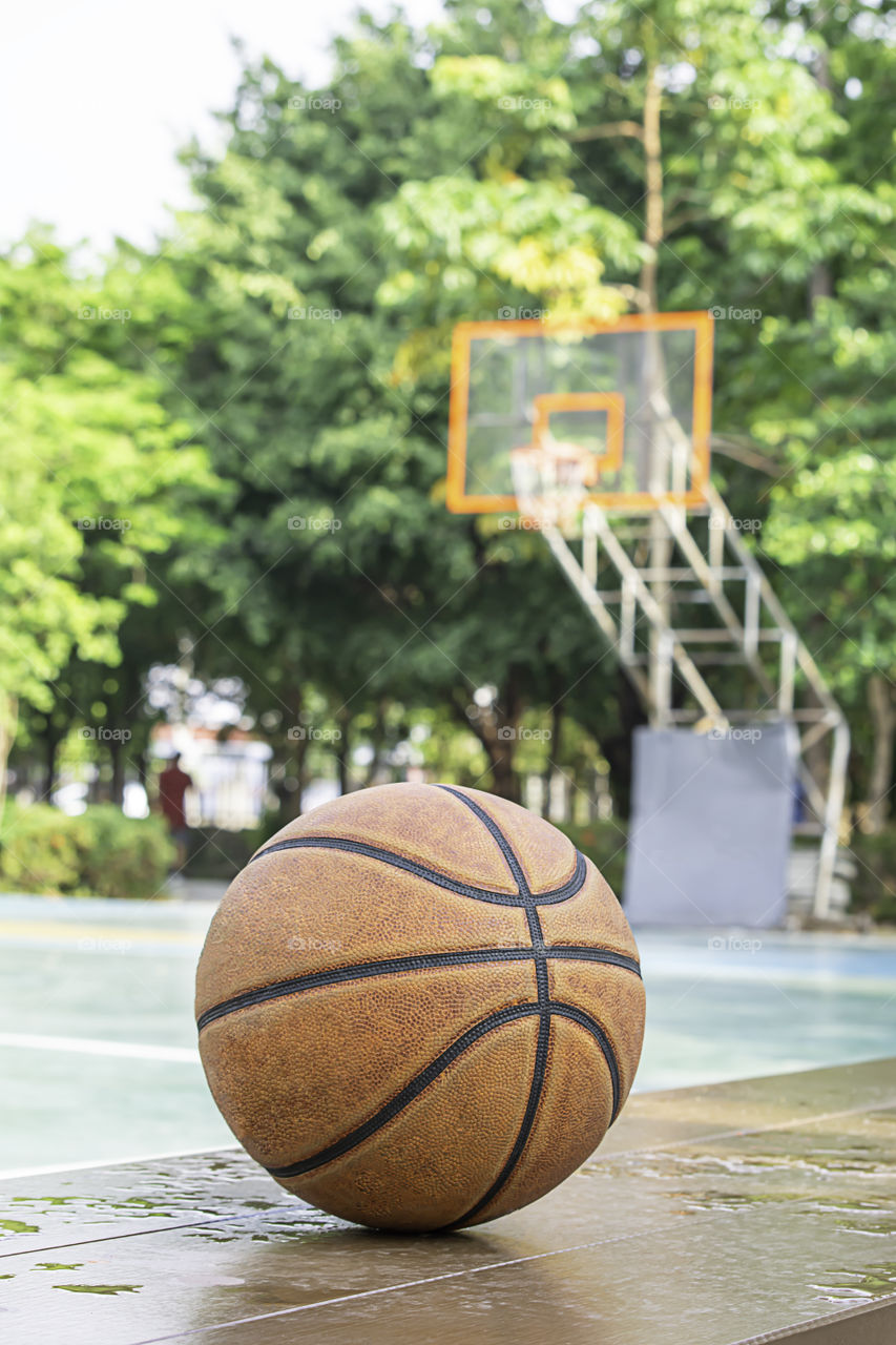Basketball leather on the wooden chair with water droplets Background basketball court and park.