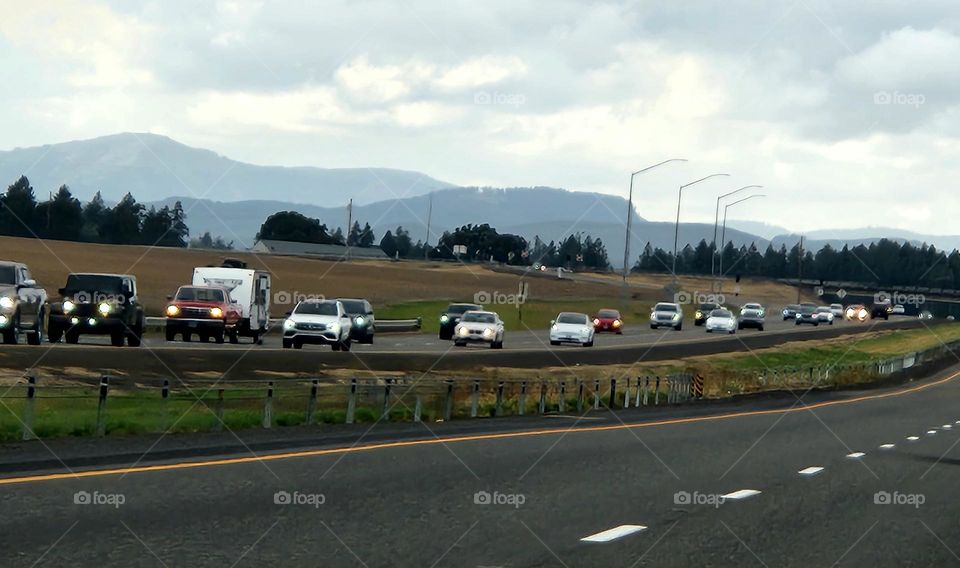 multiple cars with bright headlights driving in commuter traffic on a gray cloudy evening in Oregon