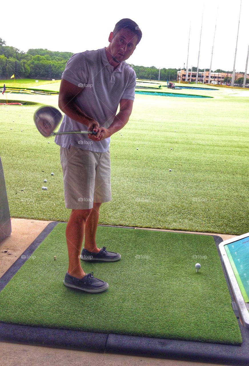 FOUR!. Man hitting a golf ball at Top Golf