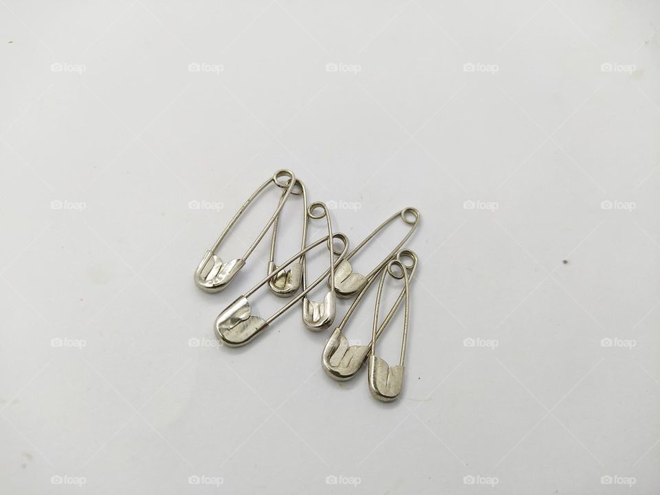 Some silver safety pins isolated on a white background