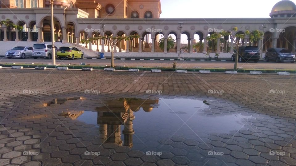 the reflection of the minaret of the mosque in the puddle of rain