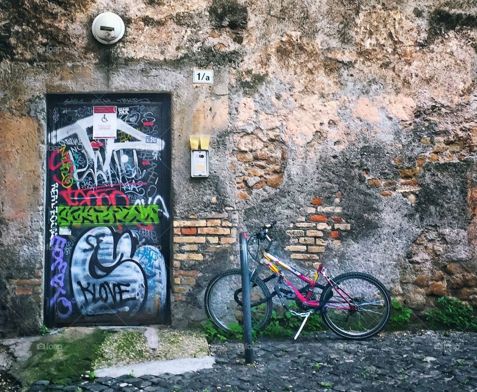 Bicycle leaning against an urban wall next to a graffiti covered door