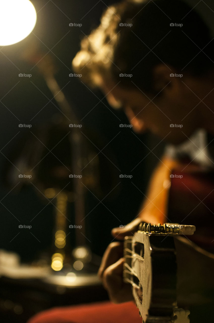 Man playing guitar under low light