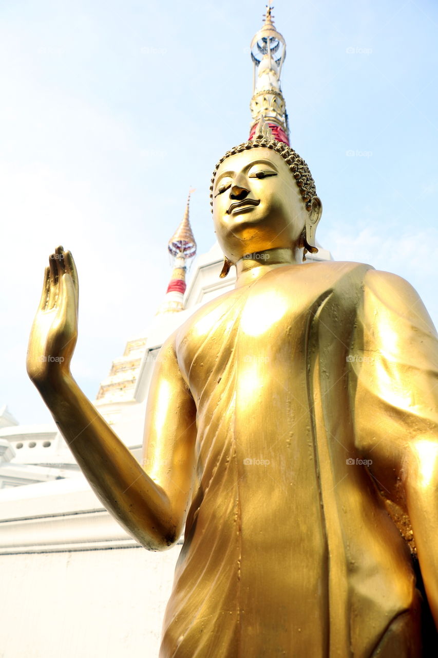 Golden standing​ Buddha​ statue​ located​ in Buddhism Temple.