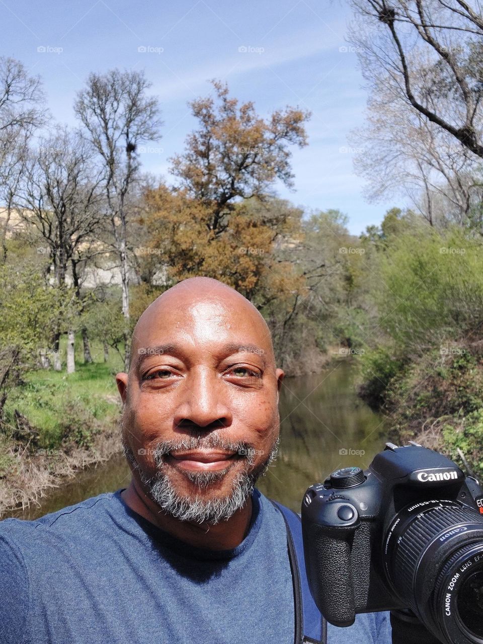 Photographer on a nature hike, standing on a bridge by a  stream in the city of Roseville California