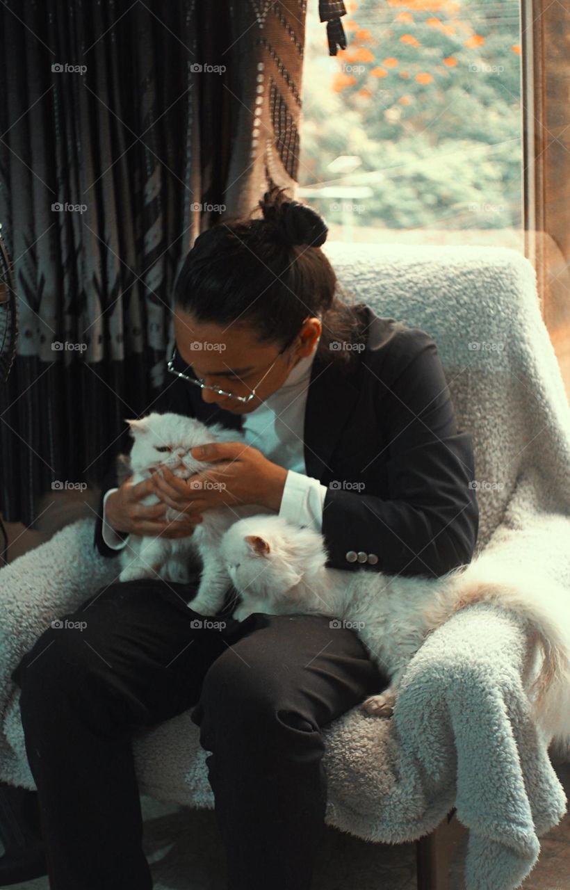 Guy cuddling with two white cats