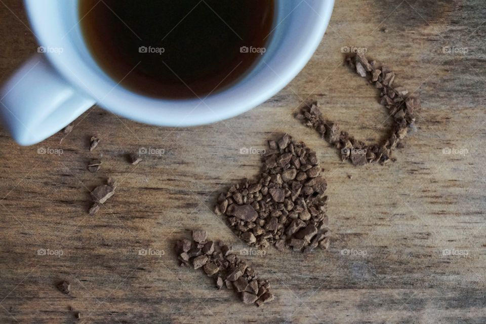 Cup of coffee with chocolates shaping heart on wooden table