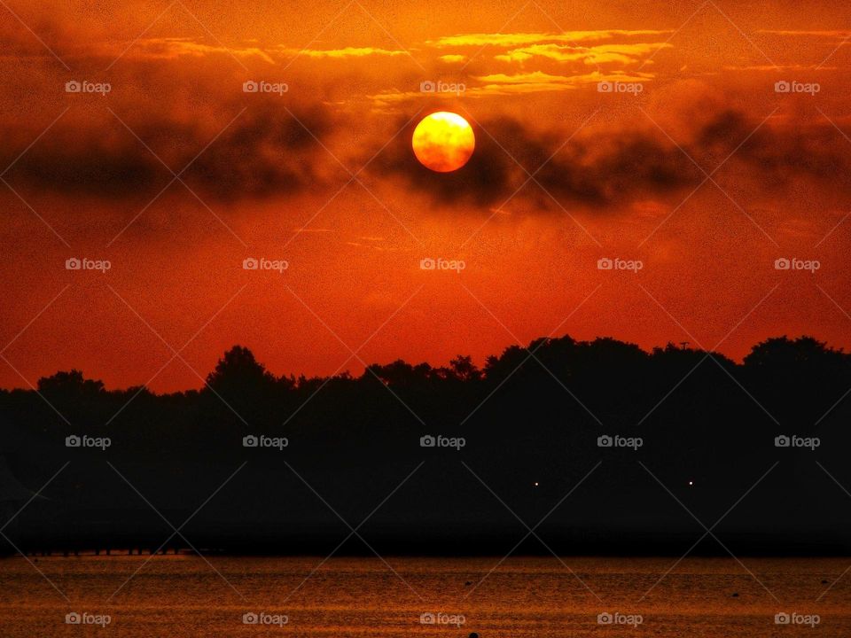 A beautiful sunrise where the sun looks like it is resting on the clouds at Cranes Roost Park in Altamonte Springs, Florida.