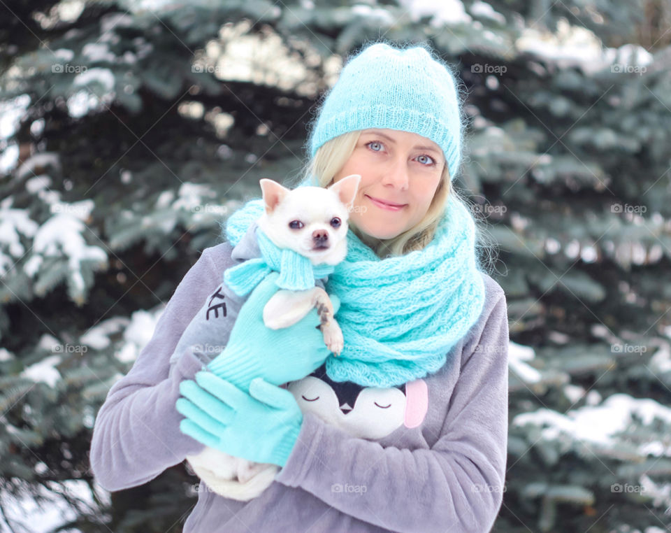 woman with a small dog in winter in turquoise scarves