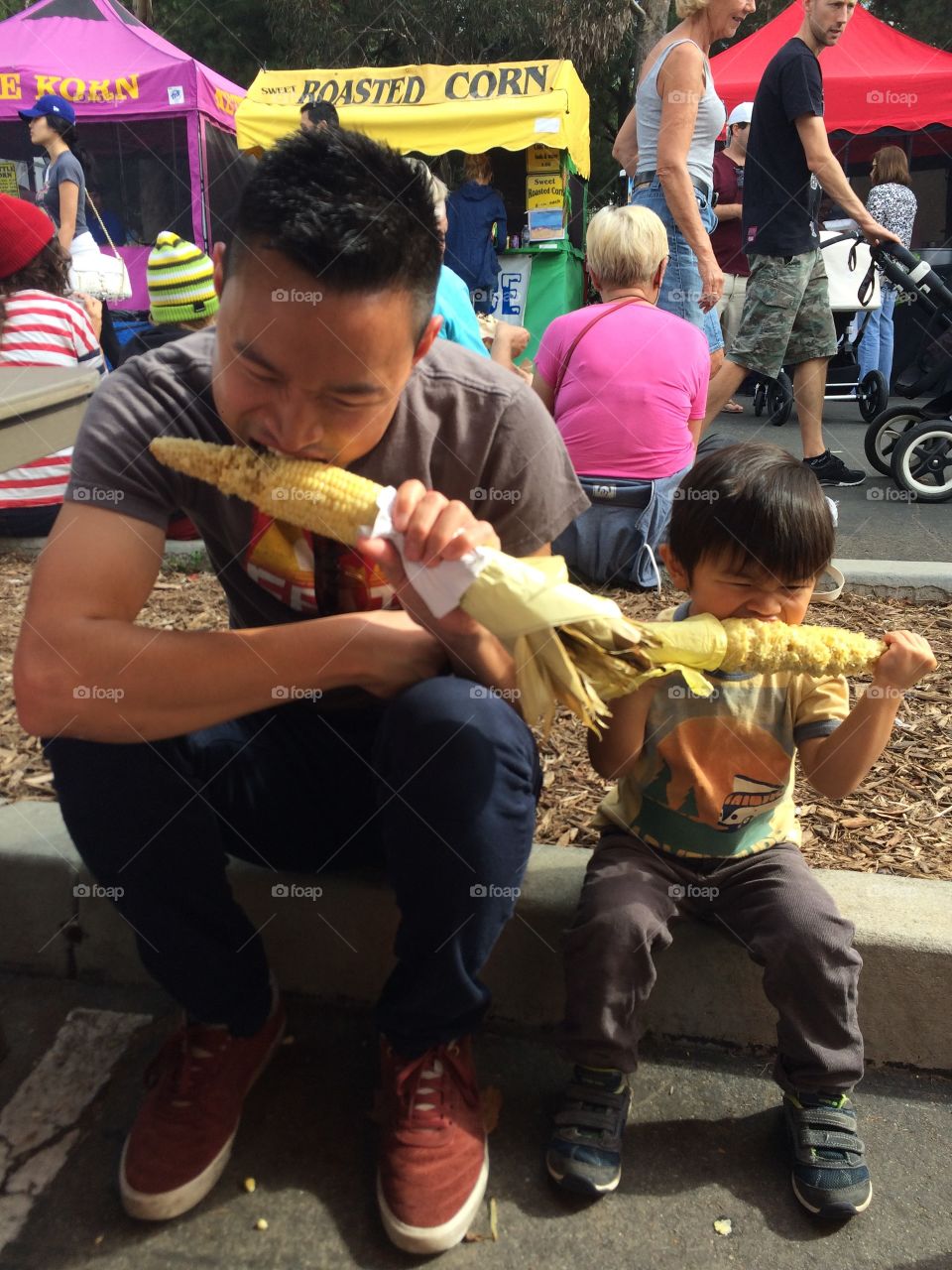 Father and son eating corn on the cob
