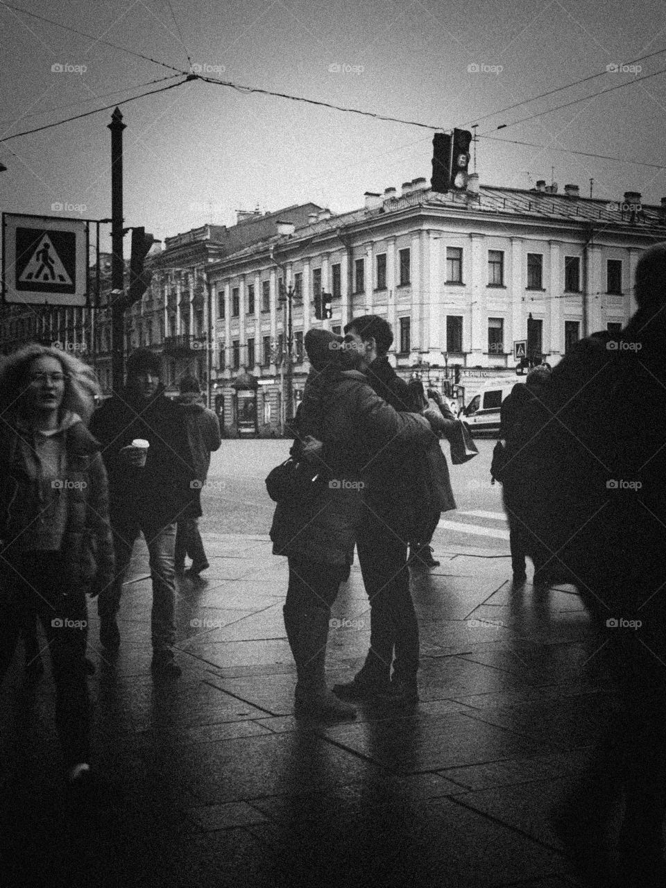 A couple is hugging on a crowded street 