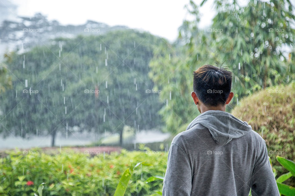 Rear view of a men watching rain