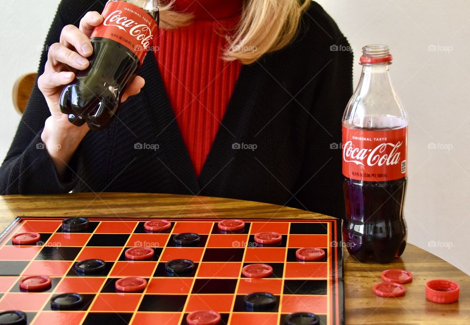 Woman drinking Coca-Cola and playing checkers 