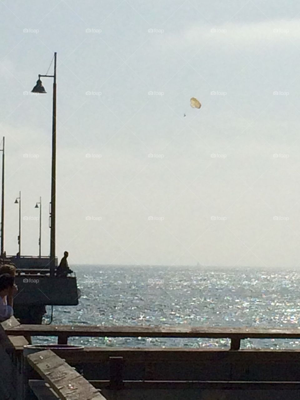 “ Peers peer on the pier” is friends watching a friend parasailing.