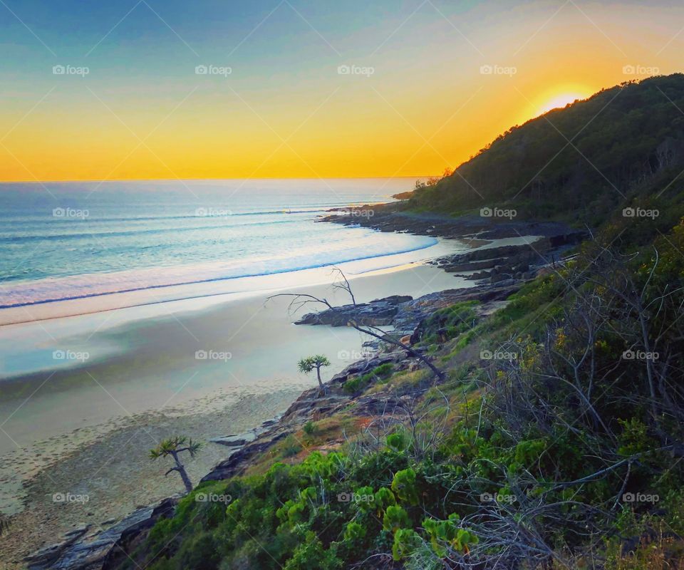 The sun peeping over the horizon behind the hill at the ocean in Australia 