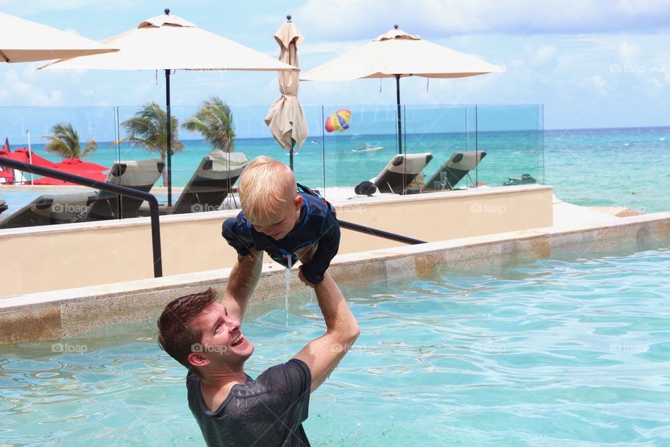 Dad and child having fun and playing on the pool 